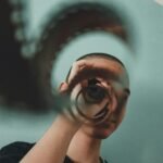 Artistic portrait of a person indoors using a vintage film reel for reflection and visual effect.